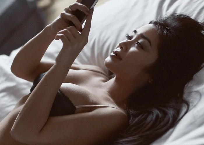woman with phone on the bed