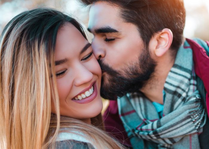 man kisses woman in cheek