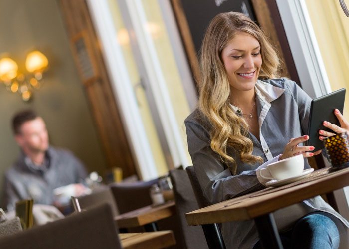 woman with cup of coffee chating by tab