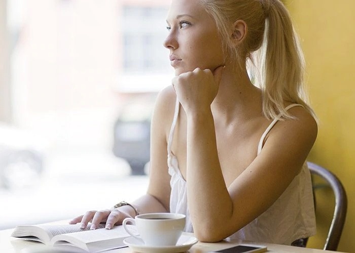 woman drinks coffee with book